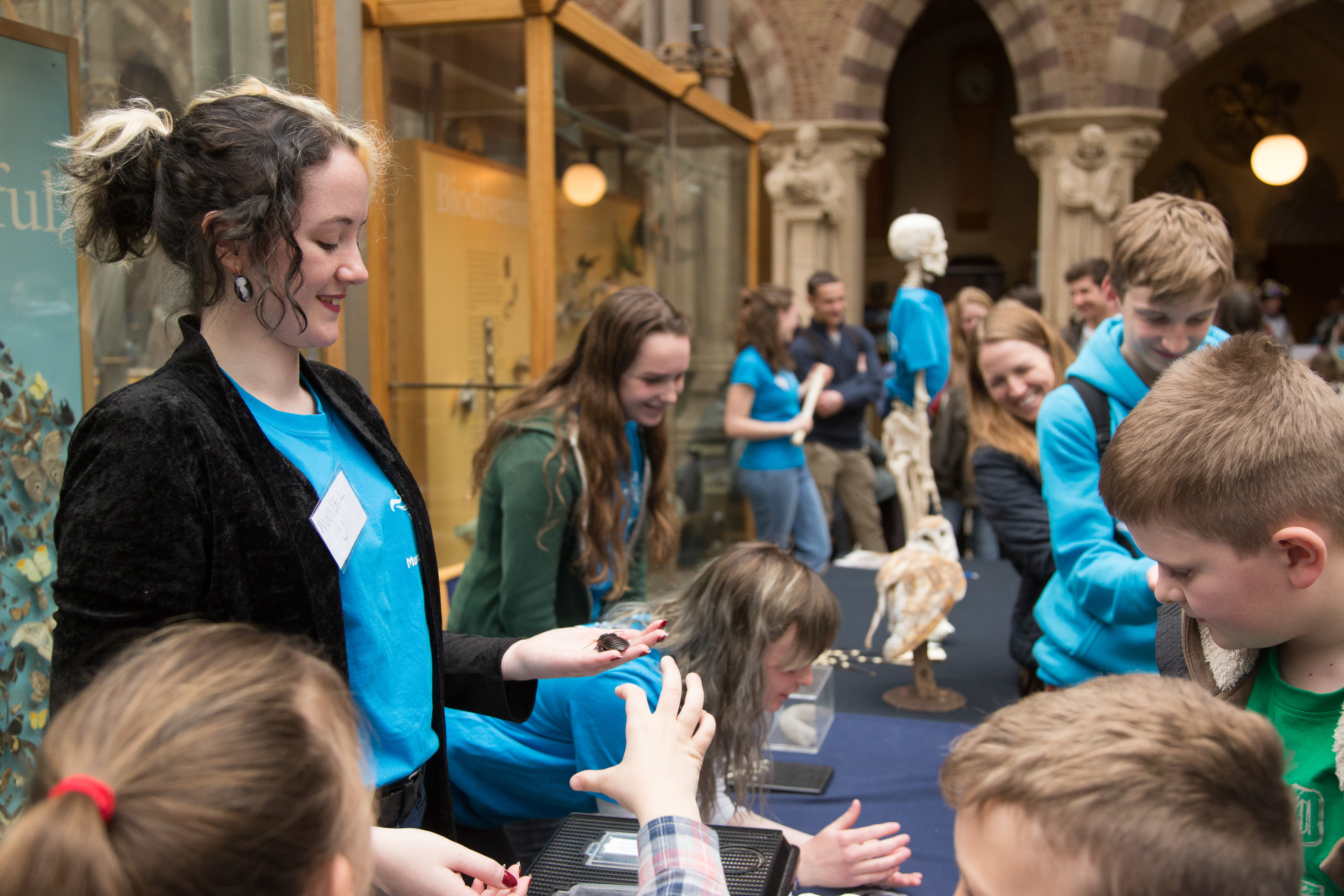 Museum staff with children looking at specimens on a table in the Museum